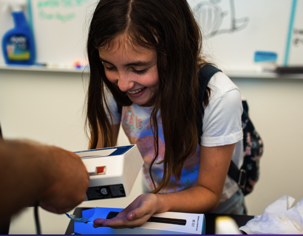 Middle School Student holding hands under magnifying glass